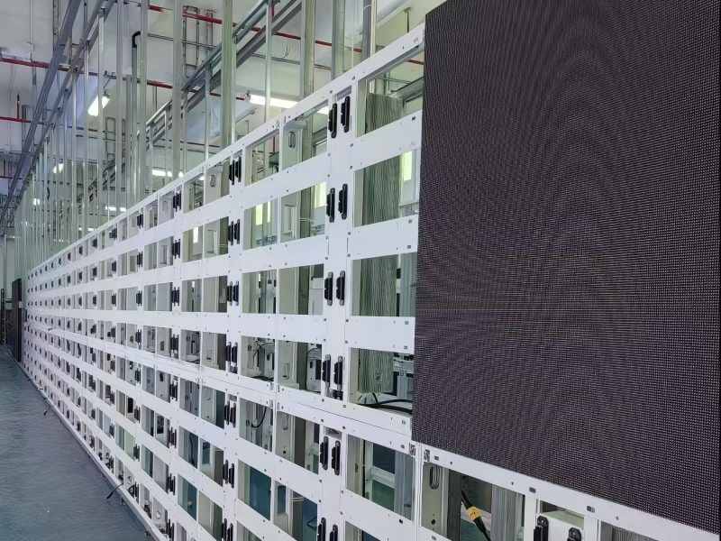 Factory production line showing rows of lightweight aluminum profile LED display frames. Front view with a single LED module installed to test fit. Designed for heat dissipation and weight reduction in outdoor fixed installations.