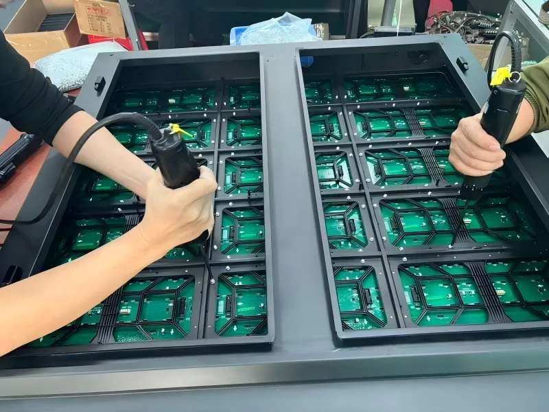 Factory technicians assembling outdoor LED modules onto the cabinet frame using electric screwdrivers. Ensuring strict torque control and IP65 waterproof sealing for outdoor durability.