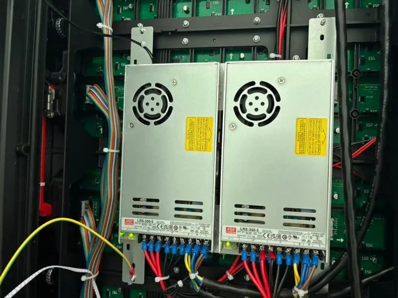 Internal view of an outdoor LED display cabinet featuring dual Genuine Meanwell power supply units (PSU) and neat cable management. High-reliability power solution for 24/7 operation.