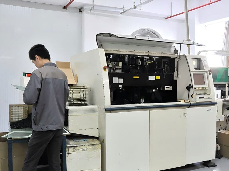 Technician operating automatic SMT machinery for LED display module production