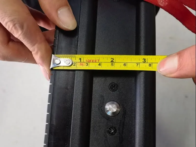 Hand holding a tape measure against the side of an outdoor LED cabinet, showing a slim profile of approximately 80mm (8cm). Demonstrating the space-saving and lightweight design of the module frame.